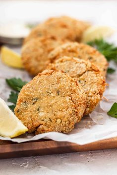 two crab cakes on a cutting board with lemon wedges