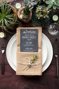 a place setting with napkins, silverware and succulents on the table