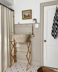 a bathroom with a basket on the floor next to a shower curtain and towel rack