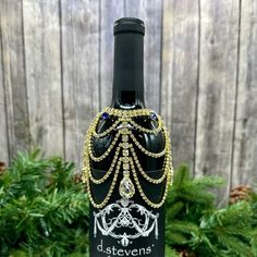 a bottle of wine that is decorated with beads and chains on it's side