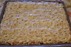 a pan filled with cheese covered food on top of a wooden table next to a flowered cloth