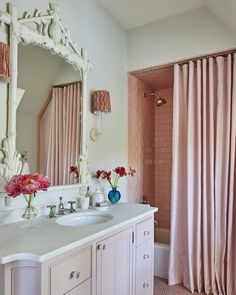 a bathroom with pink curtains and white cabinets