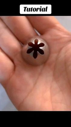 a hand holding a flower shaped object in it's palm