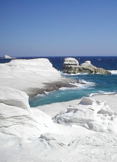 a person on skis is standing in the snow near some water and rocks,