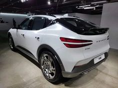 the rear end of a white car parked in a garage with no one around it