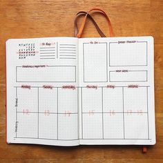 an open planner with red marker marks on it and a brown bag hanging from the side