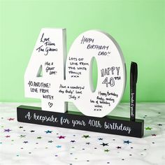 a black and white number forty birthday cake topper with writing on it, next to a pen