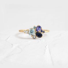 three stone ring in yellow gold with blue and white stones on each side, sitting on a white surface