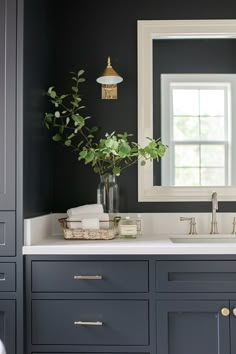 a bathroom with black walls and white counter tops, gold accents on the faucet