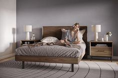 a woman sitting on top of a bed in a bedroom next to two nightstands