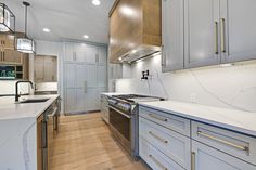 a kitchen with white counter tops and gray cabinets, along with an island in the middle