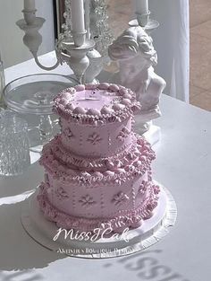 a three tiered cake sitting on top of a white table next to two candles