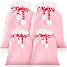 three pink bags with white pom - poms and candy canes on them