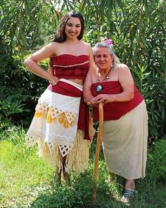 two women dressed in traditional hawaiian garb posing for a photo with their canes