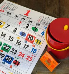 a red bucket sitting on top of a table next to a calendar