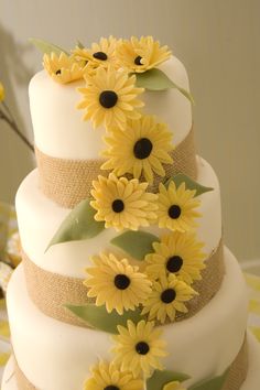 a three tiered cake with sunflowers on the side and burlap