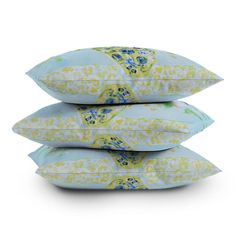 three pillows stacked on top of each other in front of a white background with blue and yellow flowers