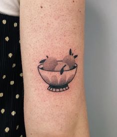 a woman's arm with a small bowl tattoo on it