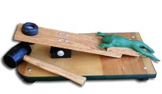 a wooden board with two pieces of wood on it and a green toy lizard laying on top