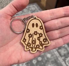 a hand holding a wooden keychain with an image of a ghost on it