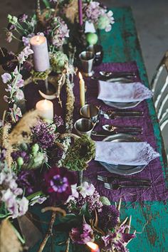 the table is set with purple flowers and candles