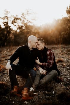 two men are sitting on the ground and one is holding his face to each other