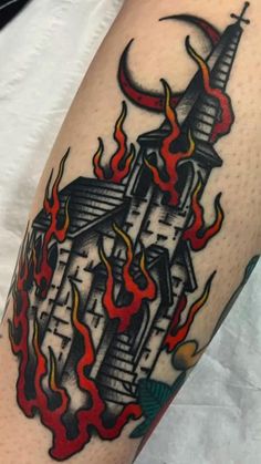 a tattoo on the leg of a man with flames and a building in the background