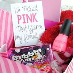 a pink teddy bear sitting inside of a box filled with candy and candies next to a sign that says, i'm ticker pink