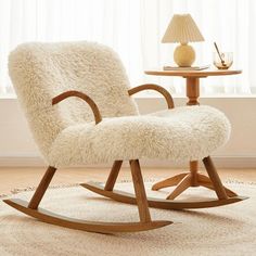 a white rocking chair sitting on top of a rug next to a table with a lamp