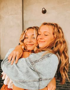 two young women hugging each other in front of a building