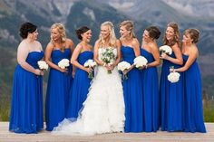 a group of women in blue dresses standing next to each other on a wooden platform