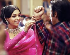 a woman in a pink sari holding onto a man's hand