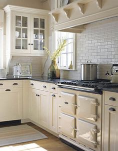 a kitchen with white cabinets, black counter tops and an oven in the center area