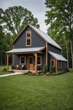 a small house with a porch and covered in wood, surrounded by green grass and trees