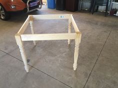 a wooden table sitting on top of a cement floor next to a car parked in a garage