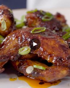 chicken wings with sauce and green onions on a white plate