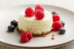 a white plate topped with a cheesecake covered in berries