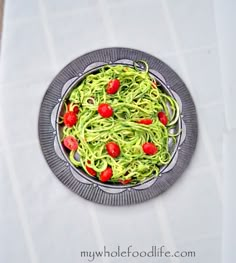 a plate filled with green noodles and tomatoes