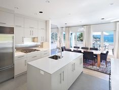 a large kitchen with an island in front of the stove top oven and dining room table