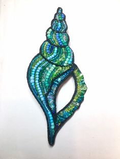 a blue and green brooch sitting on top of a white surface