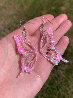 Each pair of earrings are handmade to order, therefore no two pairs are identical! However, I try to get as close as possible :) Hypoallergenic & nickel-free sterling silver plated fishhook earrings. Each butterfly wing is approximately 2 inches in length and are made with epoxy resin, iridescent pastel pink glitter, & holographic glitter ✨  These dangly sparkly resin butterfly earrings are perfect for any occasion! Color may vary slightly. Thanks for visiting my shop! 💕 Other color options are Pink Fashion Accessories, Pink Butterfly Earrings, Whimsical Iridescent Earrings With Ear Wire, Handmade Iridescent Dangle Earrings, Unique Iridescent Earrings For Party, Whimsical Pink Resin Earrings, Pink Whimsical Pierced Earrings, Cute Butterfly-shaped Jewelry For Parties, Iridescent Hypoallergenic Earrings For Party