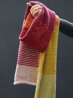 a person holding up a knitted scarf