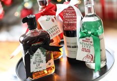 three bottles of alcohol sitting on top of a black tray next to a christmas tree