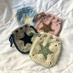 three crocheted coin purses sitting on top of a white bed next to each other