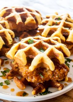 three waffles on a plate with sauce and parsley sprinkled around them