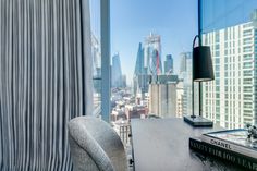 a desk with a book on it in front of a large window overlooking the city