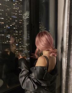 a woman standing in front of a window looking out at the cityscape and skyscrapers