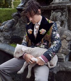 a young man holding a lamb next to a woman