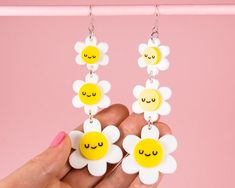 Kawaii flower statement long dangle earrings made from brightly coloured gloss yellow and white laser cut acrylic. Featuring three sleepy daisies whose faces have been laser etched and then handpainted to make them pop. Perfect to add some colour and cuteness to your summer outfit. They measure 8.5cm in length by 3.2cm at their widest point. They come on silver-plated fish hooks with the option of stainless steel hooks in the dropdown menu if you have sensitive skin. I have some smaller versions White Flower Playful Jewelry, Playful White Flower Jewelry, Playful White Flower-shaped Jewelry, Fun White Flower-shaped Jewelry, Playful White Flower Earrings, Kawaii Flower, Fish Hooks, Daisy Earrings, Long Dangle Earrings