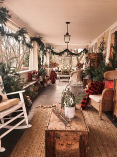 a porch decorated for christmas with wicker furniture and greenery